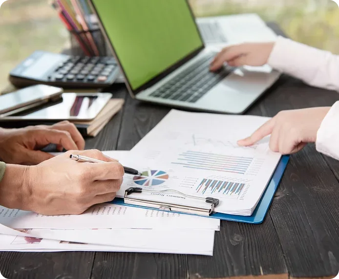 Financial reports being reviewed alongside a laptop